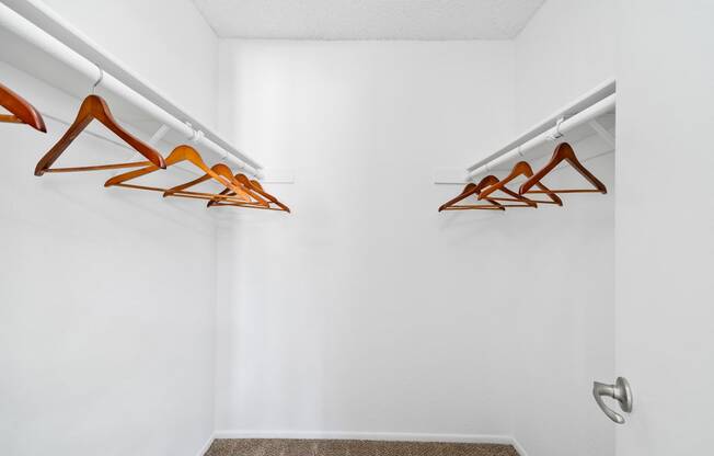 a closet with clothes hangers and a white wall
