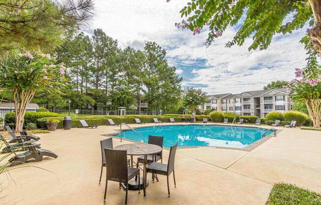 A pool area with chairs and a table.