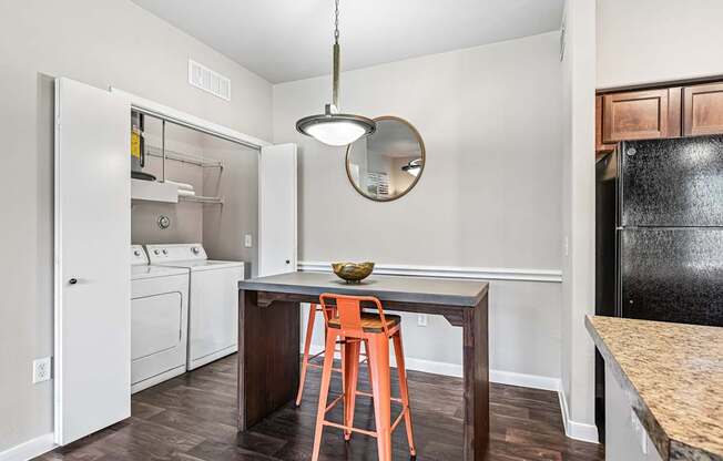 A kitchen with a black fridge, white oven, and a wooden table with a bowl on it.