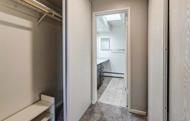 a hallway with a closet and a bathroom with a sink and a mirror