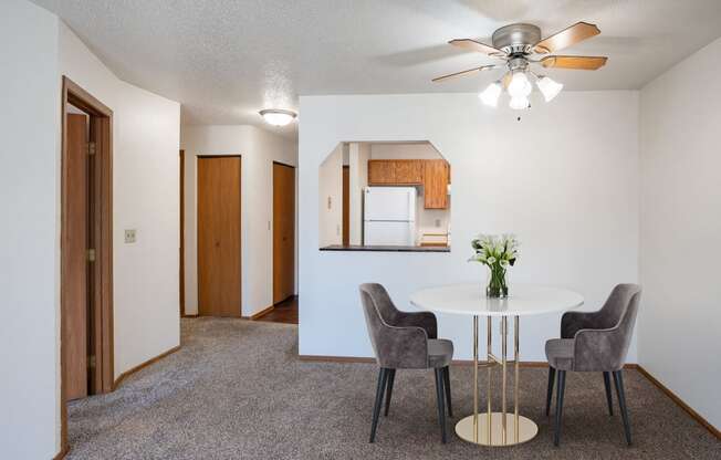 our living room and dining room with a white table and chairs and a ceiling fan. Fargo, ND Westview Towers Apartments