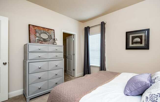 Furnished bedroom with beige walls, window, and carpet flooring at Riverstone apartments for rent in Macon, GA