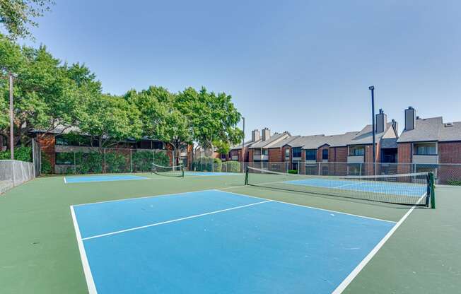 two tennis courts with apartments in the background