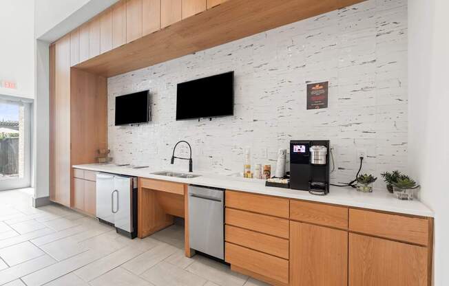 A kitchen with a white brick wall and wooden cabinets.