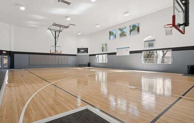 A basketball court with a wooden floor and a basketball hoop.