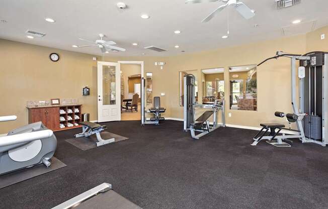 A spacious gym with a variety of equipment including a treadmill, weights, and a bench press.