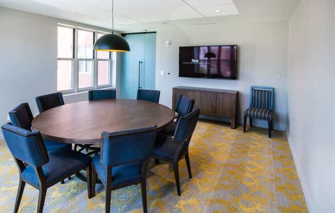 a conference room with a round table and chairs and a television