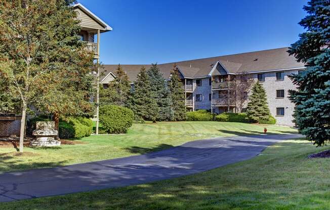 a pathway leading to an apartment building with trees and grass