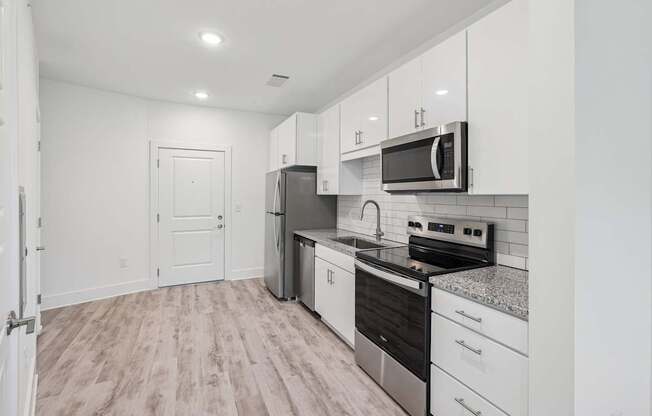 A kitchen with white cabinets and a black stove top oven at Link Apartments® CYKEL Apartments, North Carolina, 28208