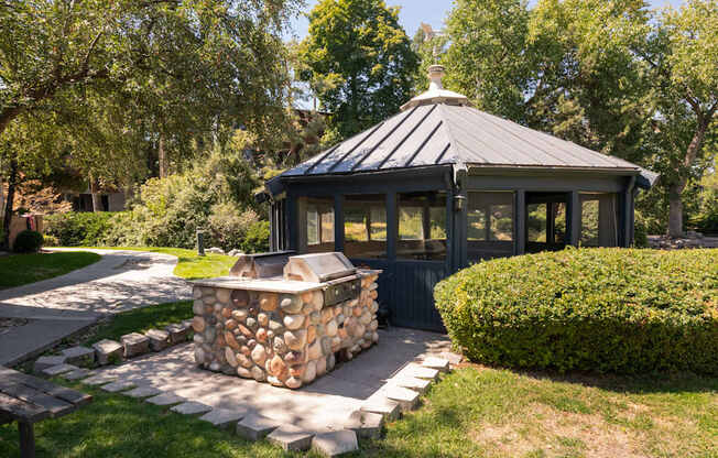 a gazebo in the backyard of a house with a stone fire pit