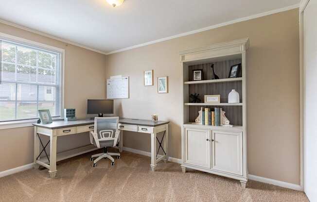 A room with a desk, chair, and bookshelf.