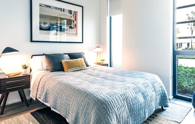 A bedroom with a large bed and a framed picture on the wall.