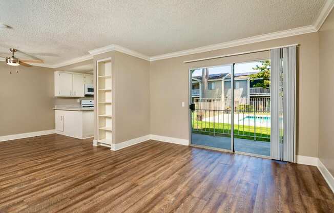 A living space with hardwood floors and a sliding glass door with a pool view..