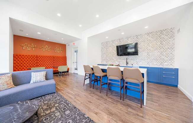 A living room with a grey couch and a blue kitchen area.