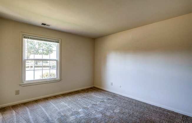 Master Bedroom with neutral colored walls and a large window  at Briarwood Apartments in Columbus, IN