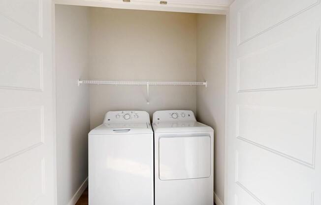 Two white washing machines in a small laundry room.