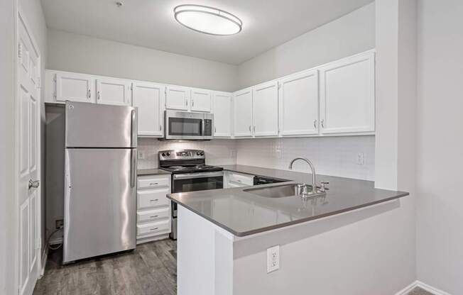 A kitchen with white cabinets and a stainless steel refrigerator.