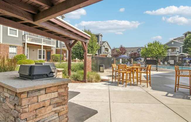 A patio with a stone pillar and wooden chairs.