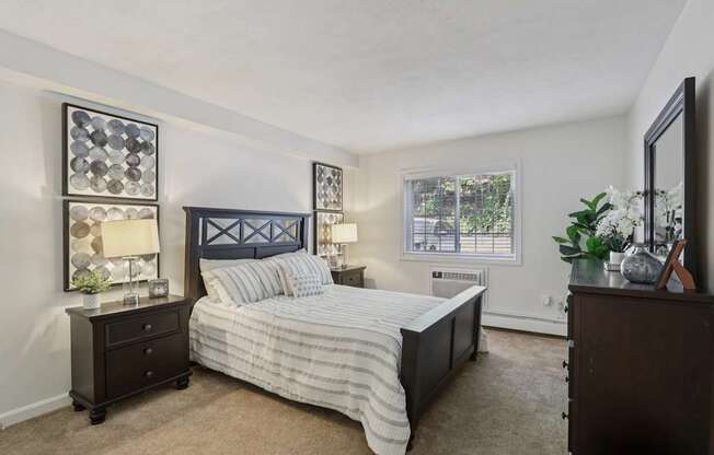 A bedroom with a bed, nightstand, and a plant on the dresser.