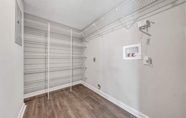 Empty walk-in closet with white shelves and wooden floors.
