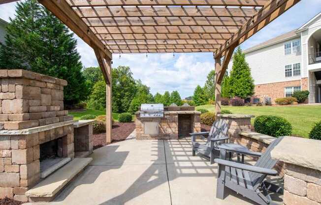 A patio with a fireplace and chairs under a wooden pergola.