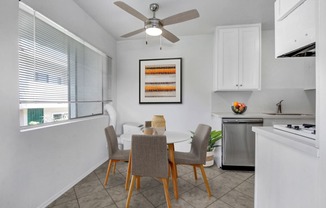 a dining area with a table and chairs and a ceiling fan