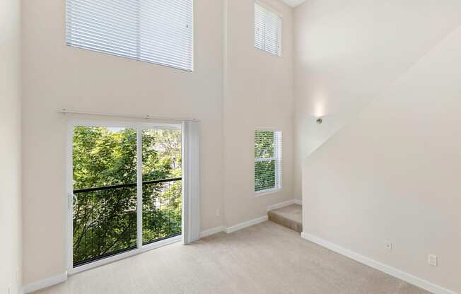 A Two-Story Loft Style Apartment with Living Area that inlcudes Large Windows and Sliding Glass Doors Leading to Outdoor Space at Sir Gallahad Apartment Homes, Bellevue, WA