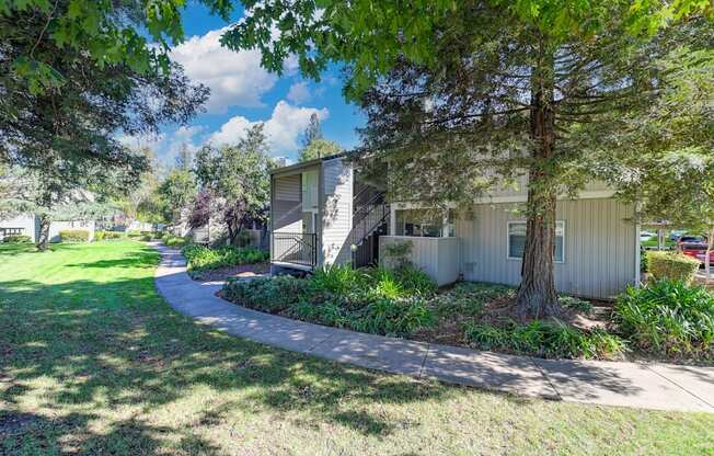 Monte Bello Community grounds with mature tress and landscaping around the building.  Concrete walk path through out the community. at Monte Bello Apartments, Sacramento, California