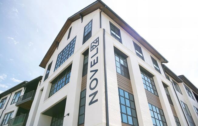 Modern apartment buildings with white bricks, wood accents, and dark window frames at Novel Cary