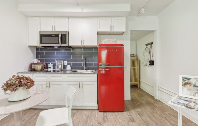 a kitchen with white cabinets and a red refrigerator