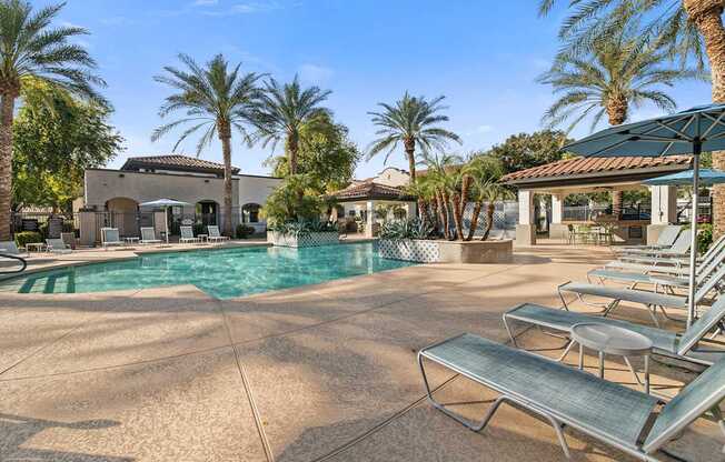 A pool surrounded by palm trees and lounge chairs.