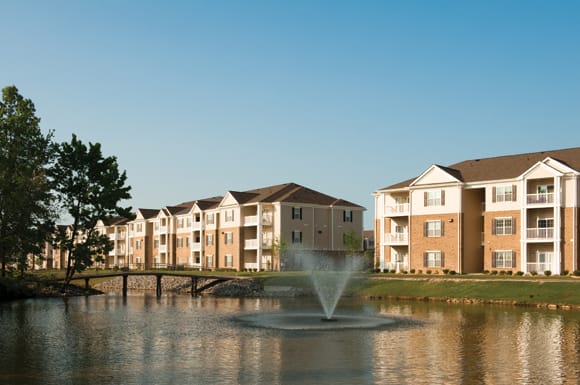 Lake surrounded by apartment buildings; fountain in the center and lakeside walking/jogging trail in the distance
