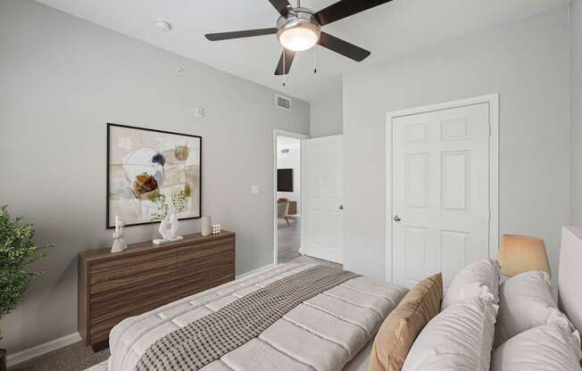 A bedroom with a bed, dresser, and a ceiling fan.