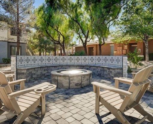 A hot tub sits in the middle of a patio with two chairs on either side.