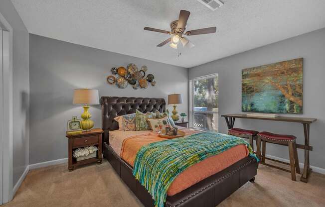 A bedroom with a bed, a table, a bench, and a painting on the wall.