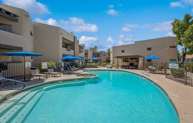 A large swimming pool in front of a building with a fence around it.
