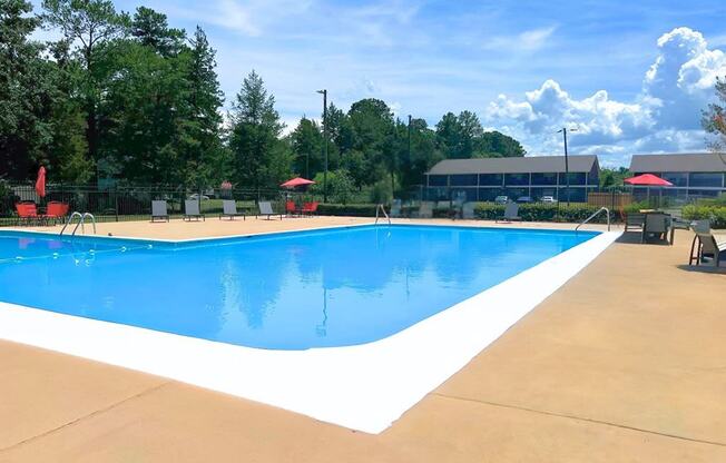 a swimming pool with chairs around it and trees in the background