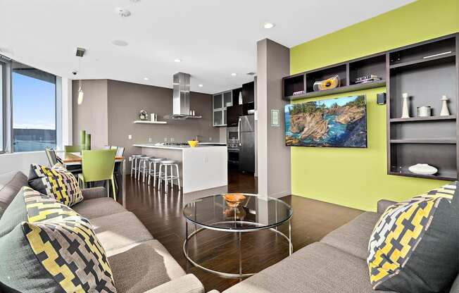 A modern living room with a grey couch and a glass coffee table.