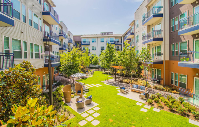an apartment courtyard with grass and trees in the middle of it at South Side Flats, Dallas, TX