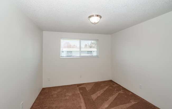 a bedroom with a window and a carpeted floor