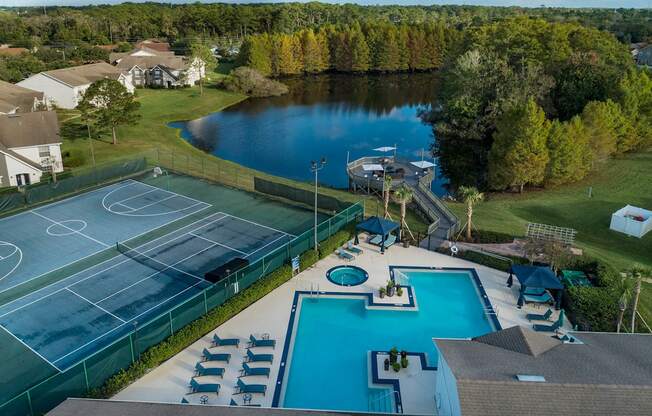 a aerial view of a pool and tennis court and a lake