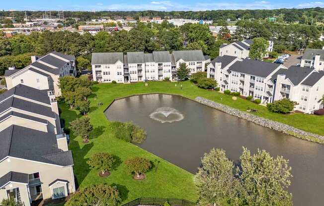 A large white building with a black roof is surrounded by a pond with a heart-shaped design in the middle.