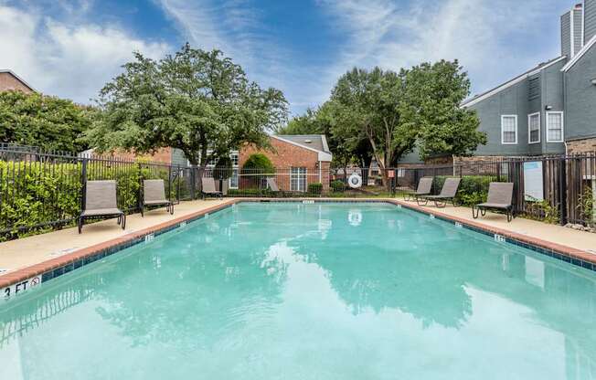 A swimming pool surrounded by trees and buildings.