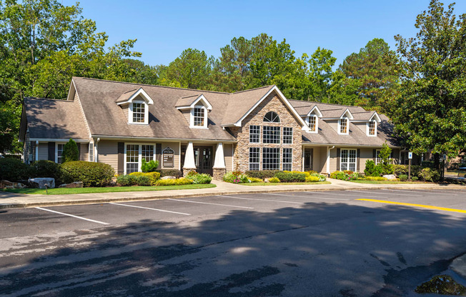 A large house with a grey roof and white trim is surrounded by trees.