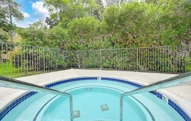 the pool is next to a fence and a yard with trees