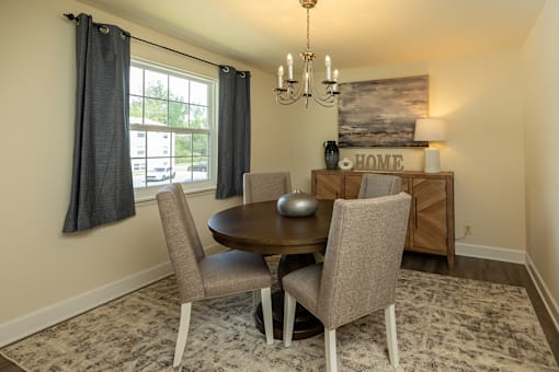 A dining room with a round table and chairs.