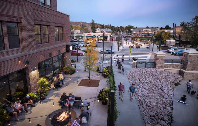 A group of people are gathered around a fire pit in a courtyard.