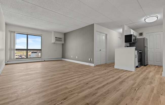 an empty living room with wood flooring and a window
