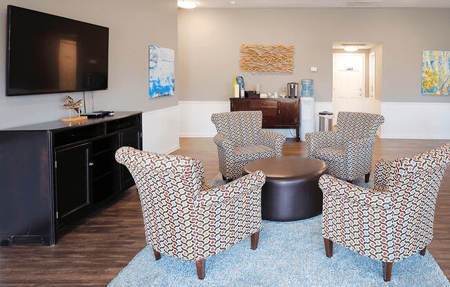 a living room with chairs and a table and a tv