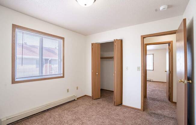 A room with a carpeted floor, a window, and a door.